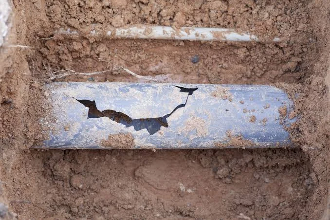 Cracked septic pipe exposed in soil during an emergency repair.