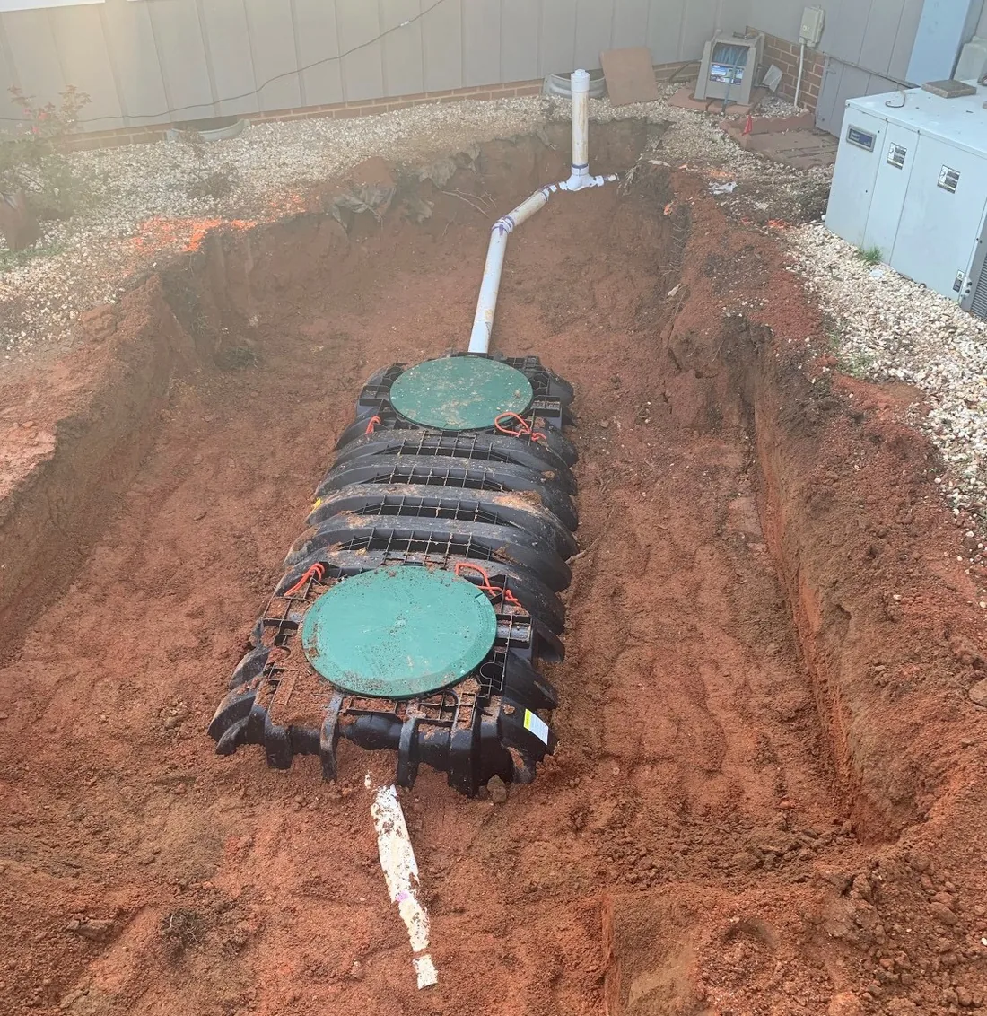 Plastic septic tank positioned in an excavation with inlet and outlet piping connected.